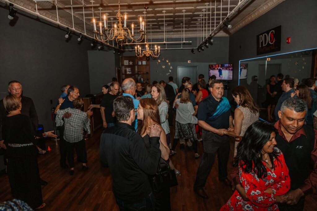 People dancing together at a social dance event, showing the benefits of dancing for health and community.